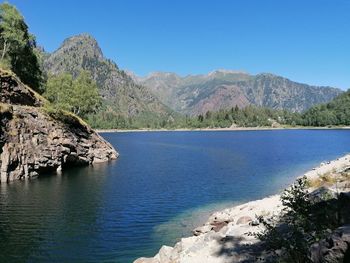 Scenic view of sea and mountains against clear blue sky