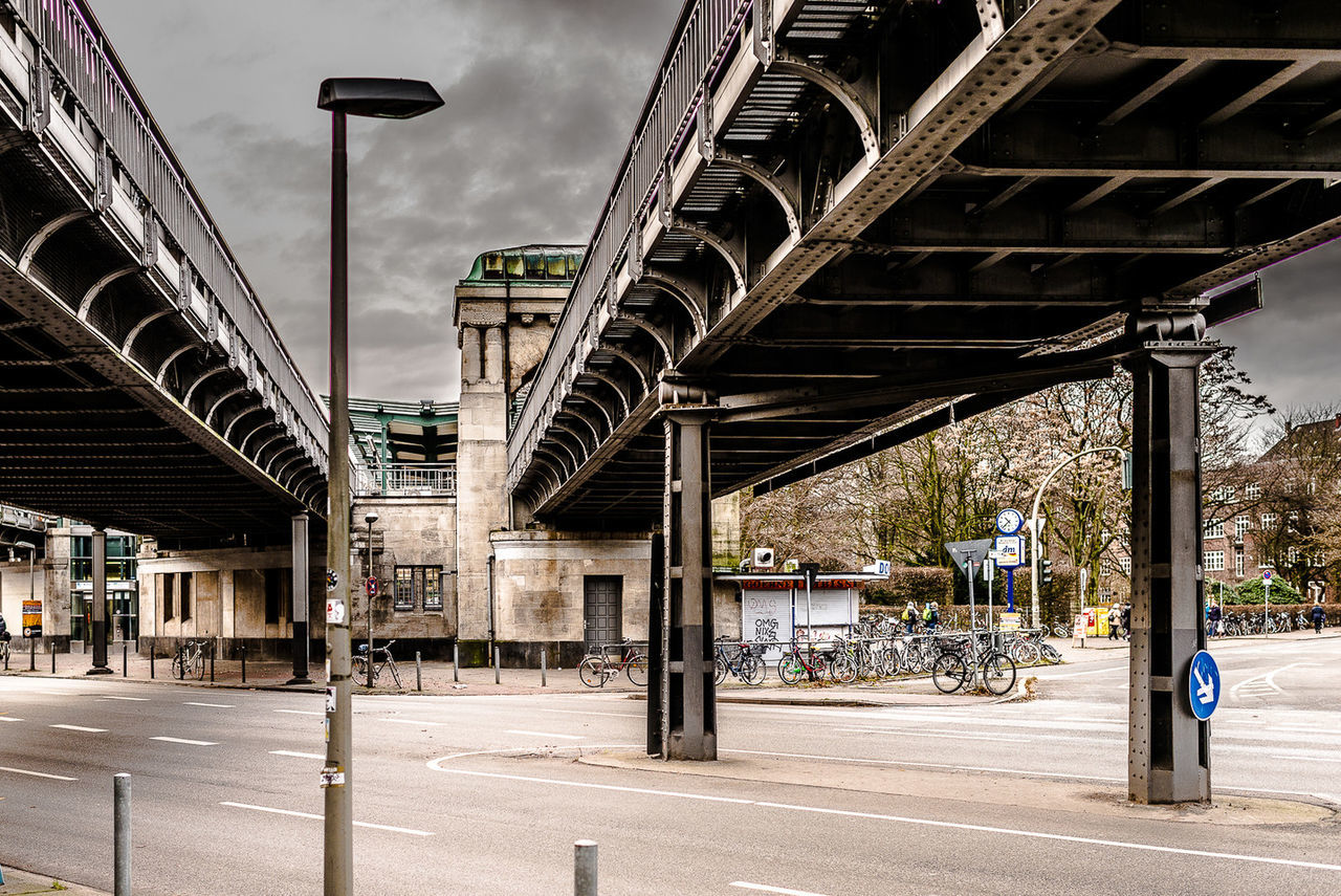 architecture, built structure, building exterior, sky, connection, bridge - man made structure, city, street light, metal, transportation, the way forward, engineering, street, incidental people, outdoors, railing, sunlight, low angle view, empty, day