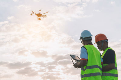 Low angle view of man using mobile phone against sky