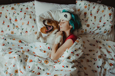 High angle view of dog and a girl relaxing on bed at home 