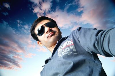 Portrait of young man wearing sunglasses against sky