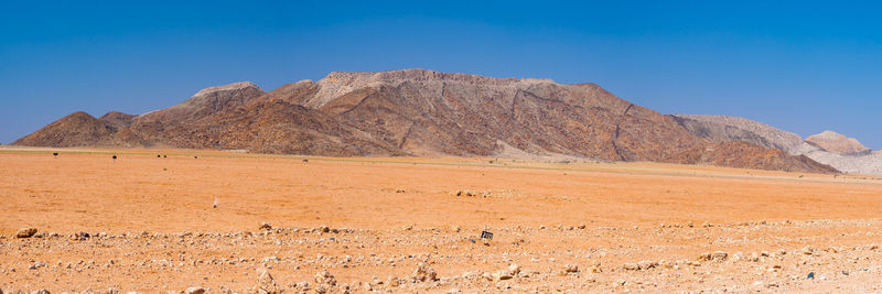 Scenic view of desert against clear blue sky