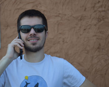 Portrait of young man wearing sunglasses against wall