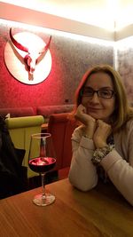 Portrait of woman with drink on table in restaurant