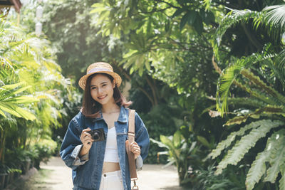 Portrait of young woman standing against plants