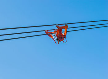 Low angle view of overhead cable against clear blue sky