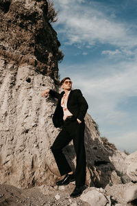 Full length of young man wearing suit standing on rock