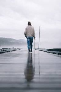 Low angle of young woman walking away on dock in the fog