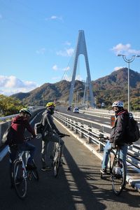 People riding bicycles across cable stayed road bridge