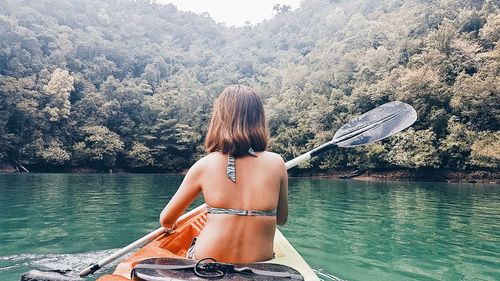 Rear view of woman in river against trees