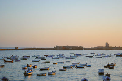 Boats moored on sea against sky sunset