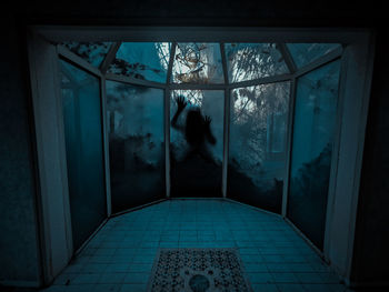 Rear view of woman standing by window