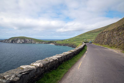 Scenic view of road by mountains against sky