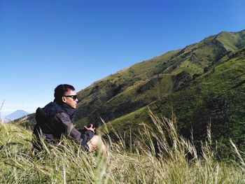 Man sitting on field against sky