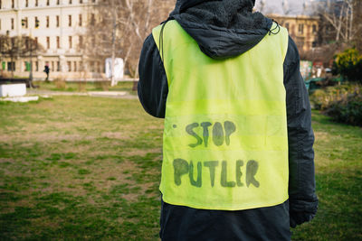 Rear view of person wearing neon vest with stop putler text message