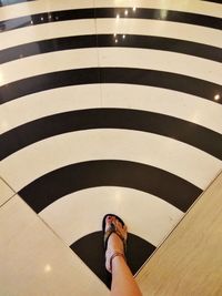 Low section of woman walking on striped floor