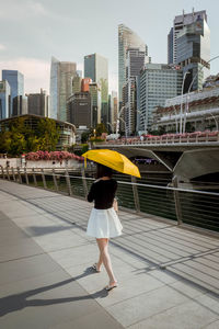 Full length of woman walking on bridge against buildings