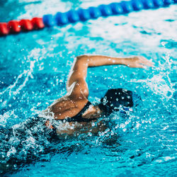 Rear view of woman swimming in pool during competition