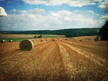 Hay bales on field against sky