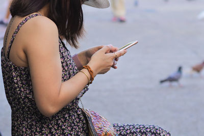 Midsection of woman using mobile phone while sitting on seat
