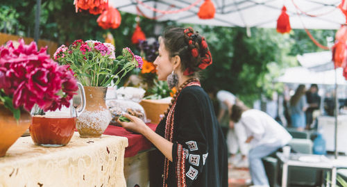 Side view of woman standing by flowering plants