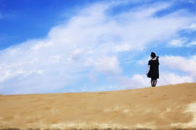 Low angle view of woman walking at tottori sand dunes against sky