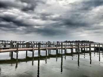 Wooden posts in sea against storm clouds