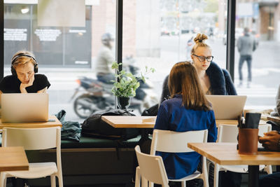 Customers sitting against window at cafe