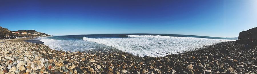 Panoramic view of beach against clear blue sky