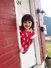 Portrait of smiling girl standing against red door