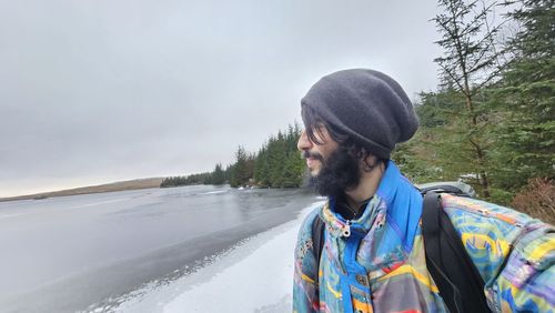 Side view of young woman standing against waterfall