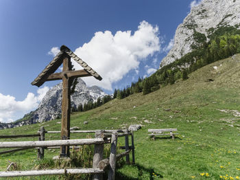 Cross on field against sky and mountains 