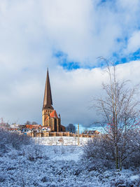 Church by building against sky during winter