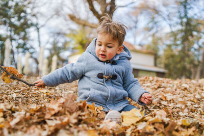 Cute boy on leaves during autumn