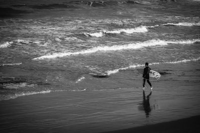 Man with surfboard walking towards sea