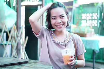 Portrait of smiling young woman having drink in cafe