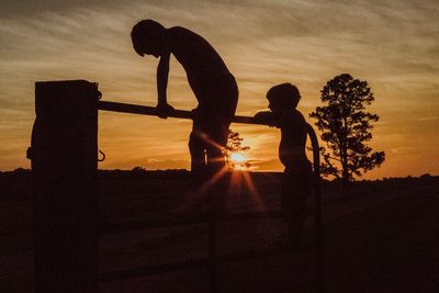 Silhouette children playing against sky during sunset