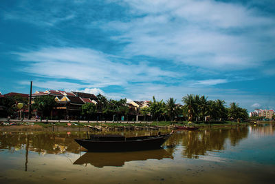 Boat moored in lake by building against sky