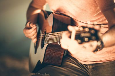 Midsection of man playing guitar