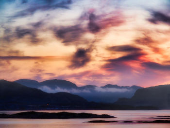 Scenic view of dramatic sky over silhouette mountains during sunset