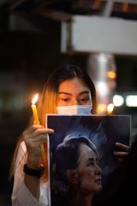 Portrait of woman holding camera at night