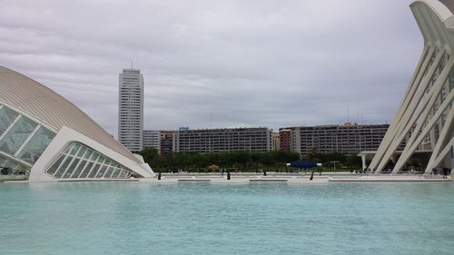 Modern buildings by swimming pool in city against sky