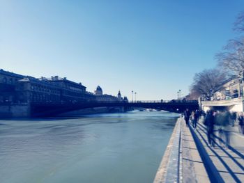 Bridge over river in city against clear sky