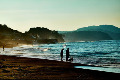 People on beach by sea against sky