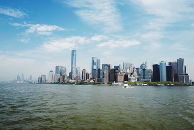 Sea and buildings in city against sky