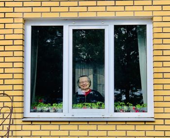 Portrait of woman seen through window of house