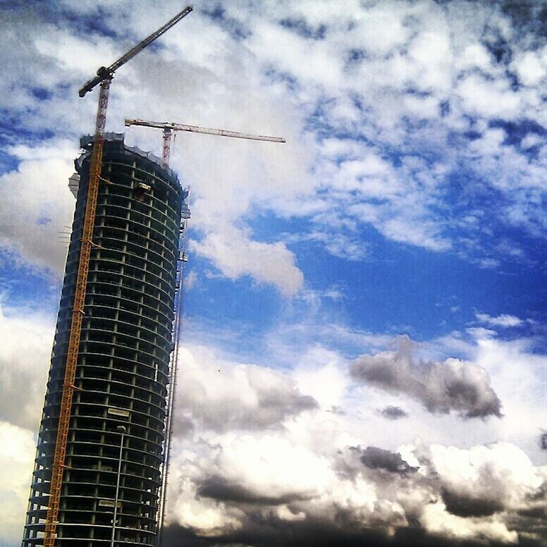 sky, cloud - sky, building exterior, low angle view, architecture, built structure, cloudy, tall - high, tower, crane - construction machinery, fuel and power generation, technology, development, industry, cloud, construction site, renewable energy, weather, alternative energy, windmill