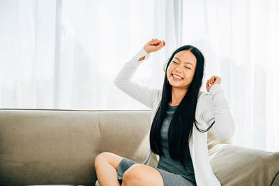 Young woman sitting on sofa at home