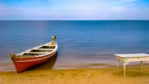 Boat moored on beach against sky