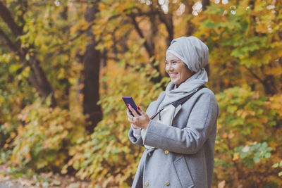 Man using mobile phone while standing on tree